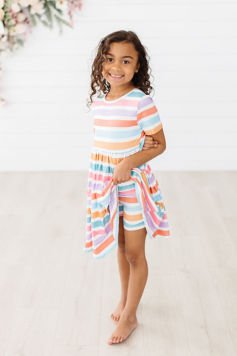 Young girl posing confidently in a Spring Stripes Short Sleeve Pocket Twirl Dress for Girls, featuring vibrant stripes and a fun twirl skirt, a perfect twirl dress for girls.
