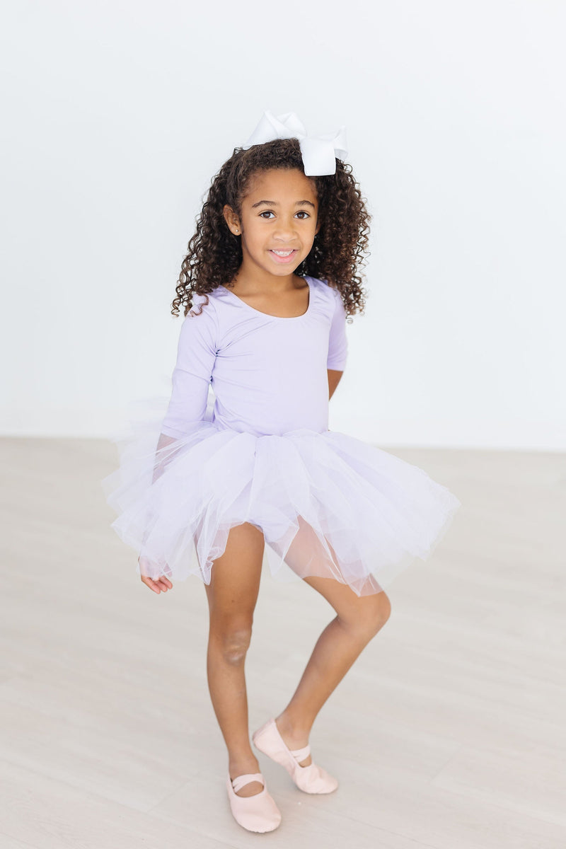 Charming girl posing in the Lavender 3/4 Tutu Leotard, showing off her fluffy tutu and playful spirit with a rosy smile.