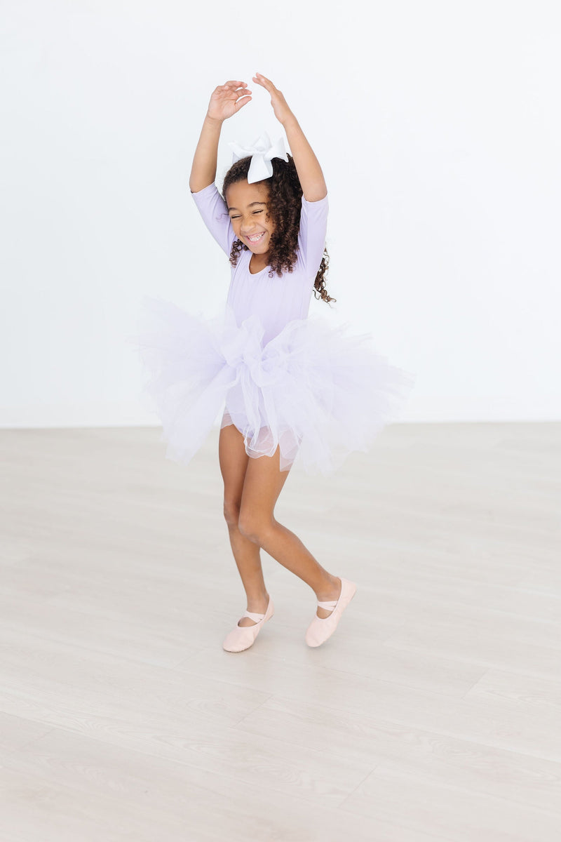 Joyful girl in motion wearing the Lavender 3/4 Tutu Leotard, twirling with glee in her fluffy tutu, perfect for dancing and fun.