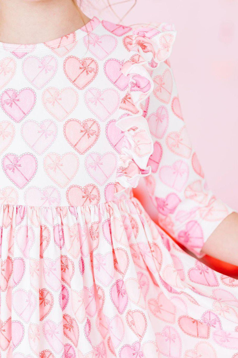 Close-up of the Melt My Heart 3/4 Sleeve Ruffle Twirl Dress featuring playful heart patterns and ruffles, perfect for inspiring twirls and smiles every day.