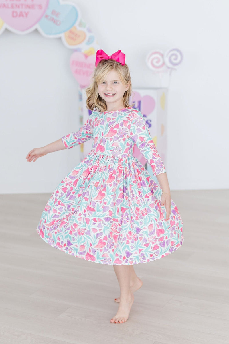 Group of kids wearing the Watercolor Hearts 3/4 Sleeve Pocket Twirl Dress and matching Twirl Shorts.