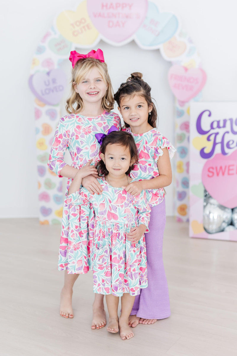 Young girl twirling in the Watercolor Hearts 3/4 Sleeve Pocket Twirl Dress enjoying playtime.