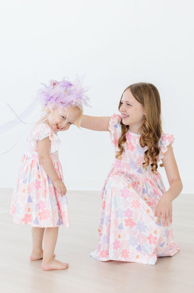 Sweet moment of a child dancing in the Castles & Rainbows Flutter Sleeve Twirl Dress, perfect for playful adventures and celebrations.