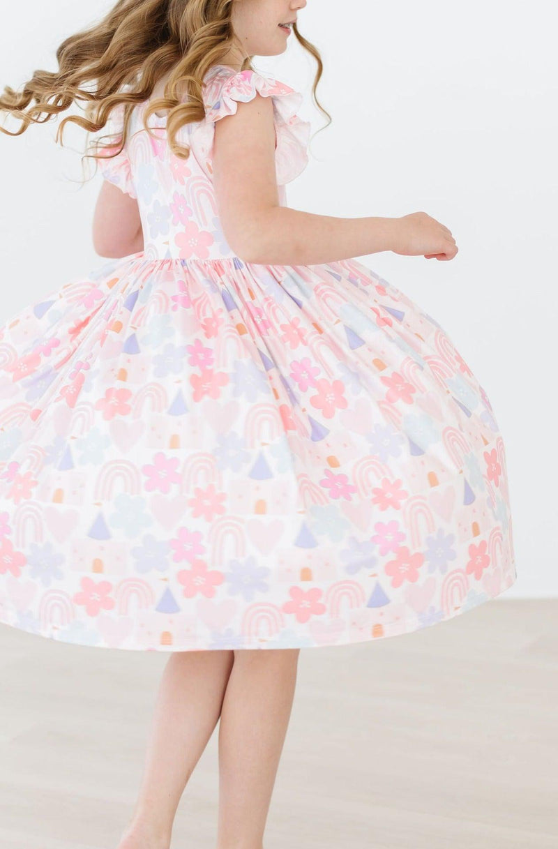 Playful girl twirling in the Castles & Rainbows Flutter Sleeve Twirl Dress for Girls by Mila & Rose, capturing the joy and comfort of childhood adventures.