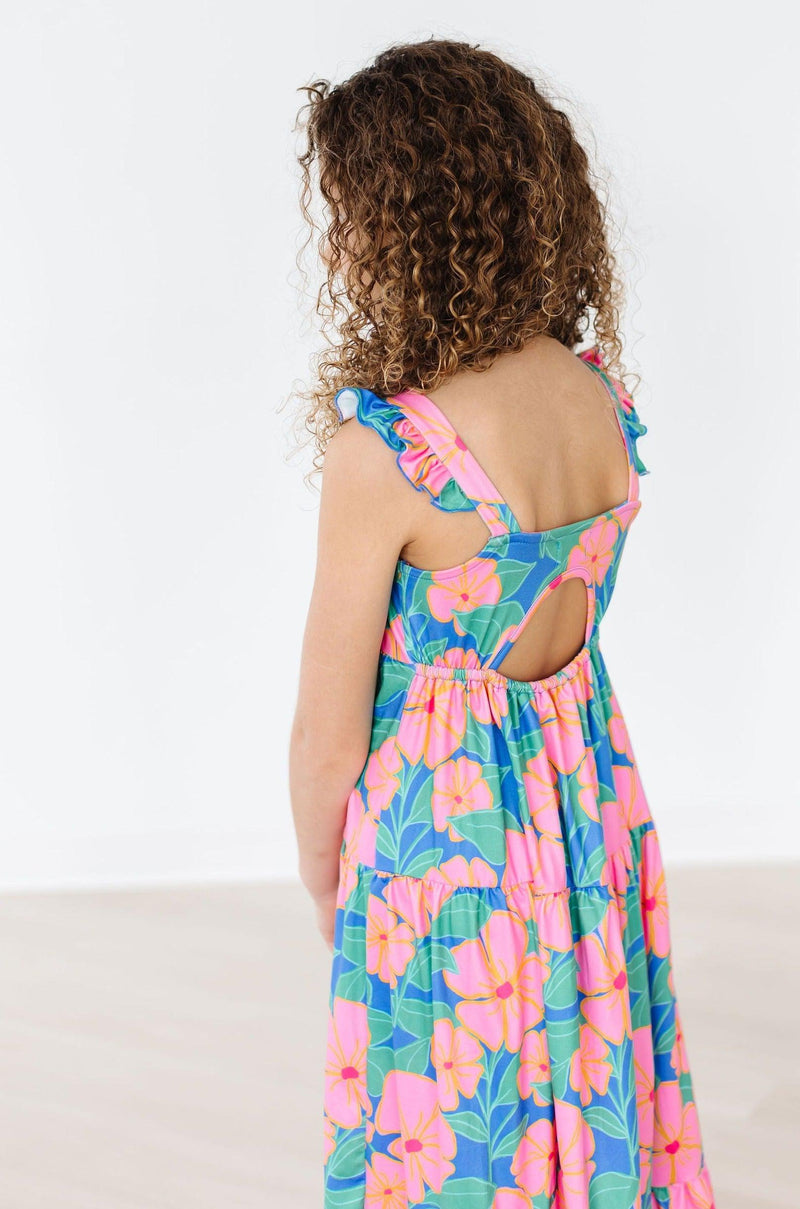A back view of a girl in the Luau Floral Ruffle Maxi Dress, emphasizing the cute cutout design and ruffle details, ideal for summer adventures.