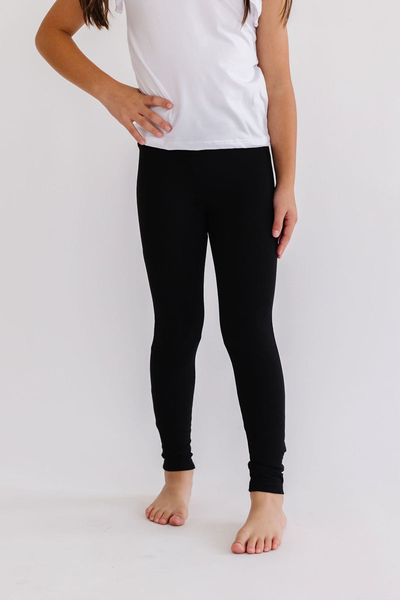 Girl confidently modeling Comfy-Fit Black Leggings for Girls, highlighting the comfortable fit and sleek design paired with a simple top.