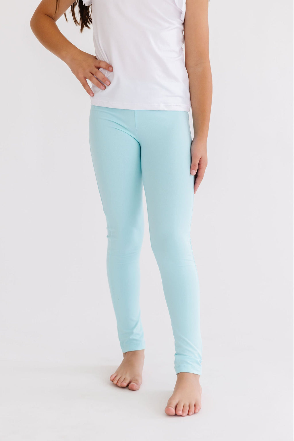 A girl wearing chic aqua leggings for girls, highlighting their snug fit and vibrant color, perfect for active play and stylish outfits. These aqua leggings for girls offer comfort and flexibility for every adventure.