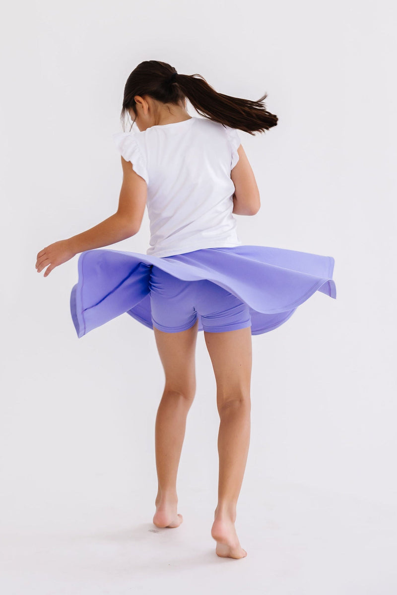 A lively girl spins in the Periwinkle Twirl Skort by Mila & Rose®, featuring attached shorts for playful movement and a charming silhouette.