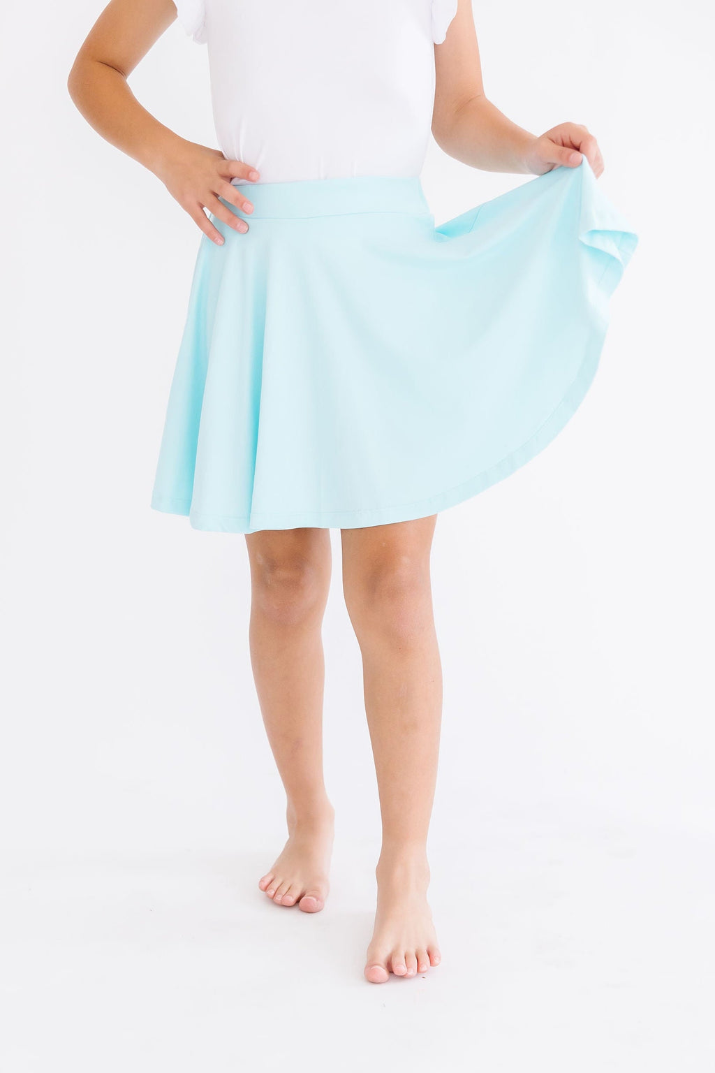 Aqua Twirl Skort by Mila & Rose®, worn by a young girl, showcasing its flowy design as she playfully holds the skirt.