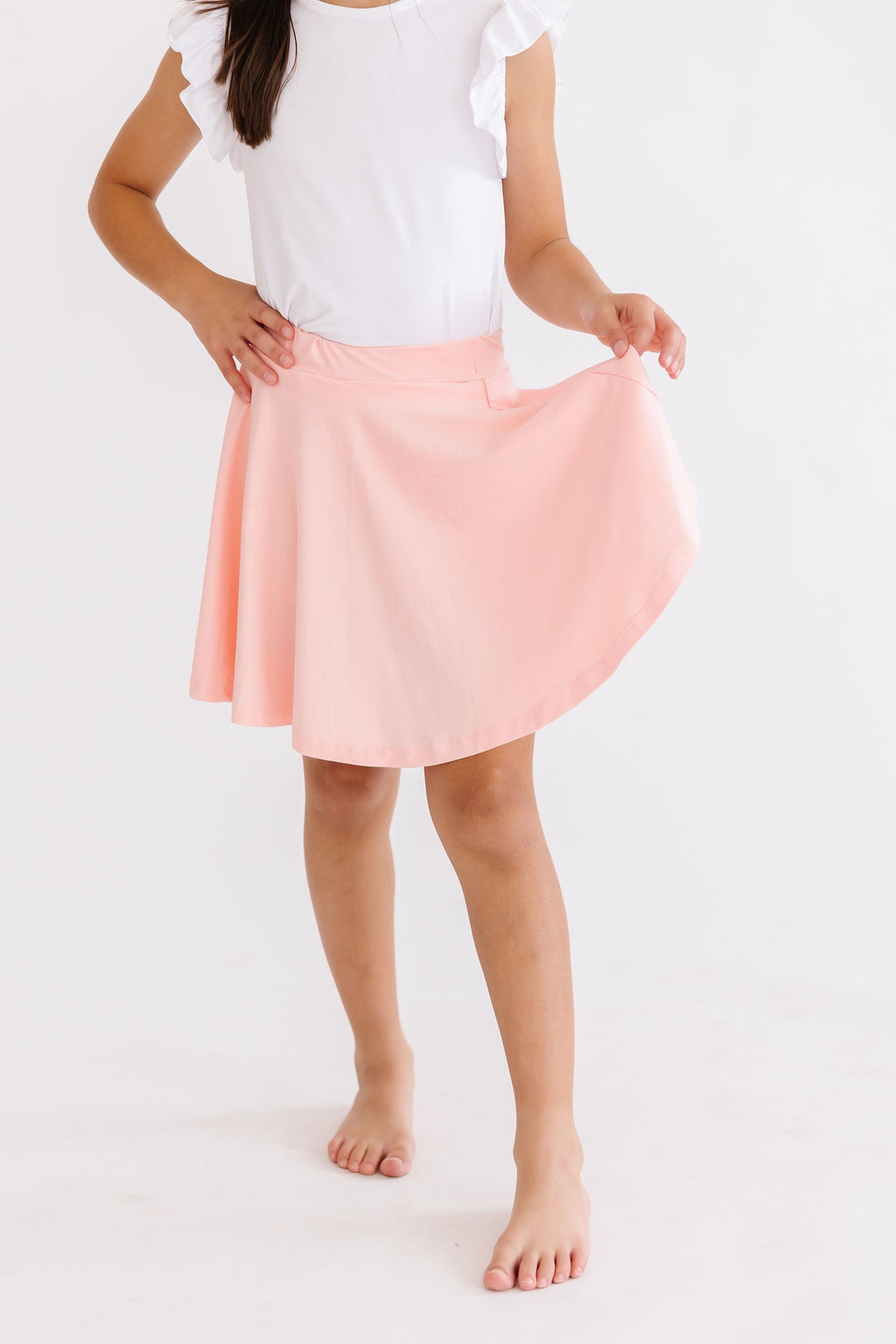Girl twirling in the Peach Twirl Skort, showcasing its playful design that allows for endless fun and comfort.