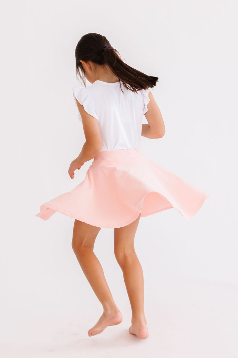 Girl caught mid-twirl in the Peach Twirl Skort, demonstrating the skort's blend of style and practicality for active play.