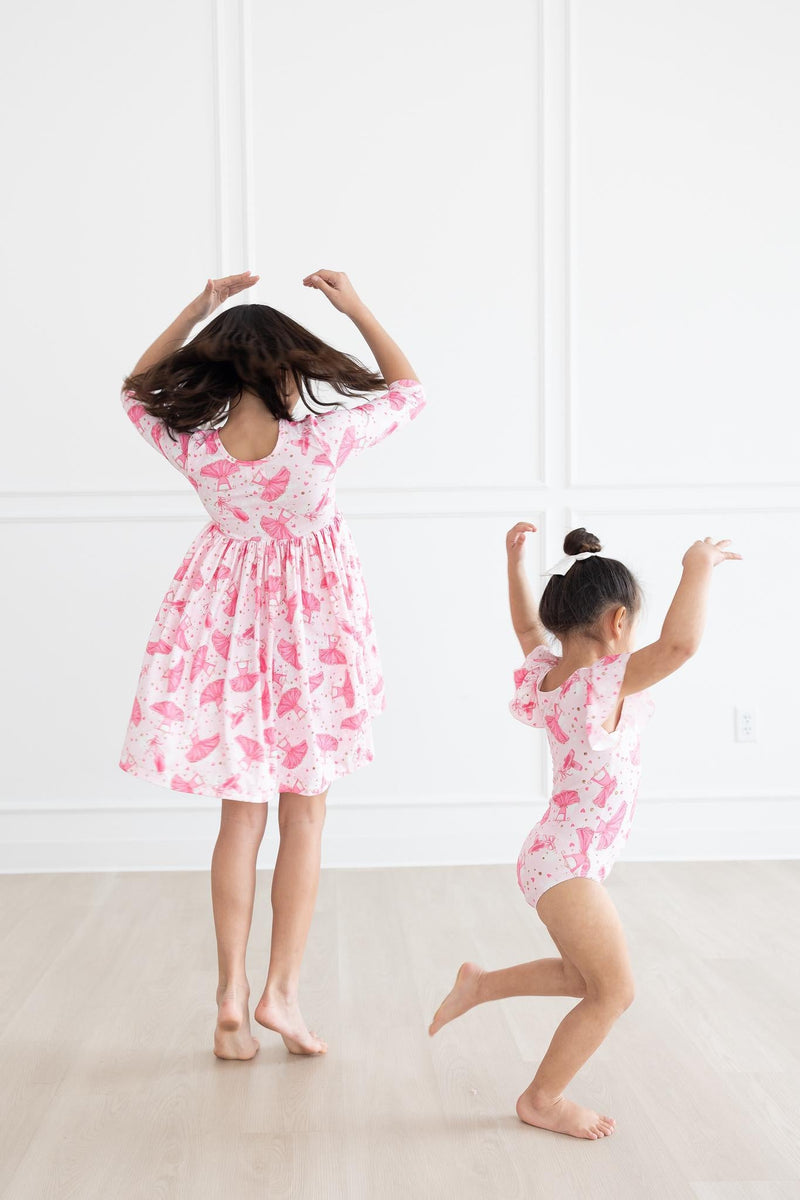 Back view of the Pirouette 3/4 Sleeve Pocket Twirl Dress as two girls dance playfully, demonstrating the dress's twirl feature and fun design.