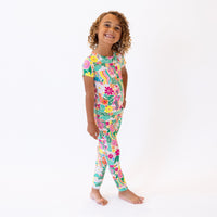 The Second-Skin 2-Piece Short Sleeve Pajama in Rainbow Daisy Babe worn by a smiling child.