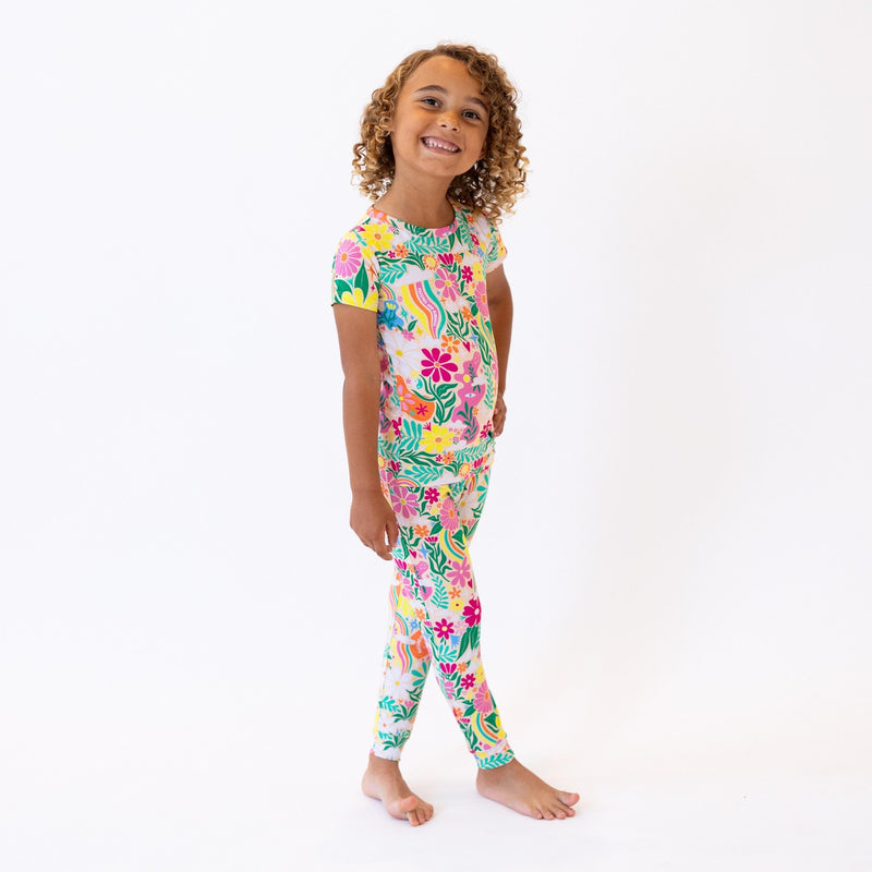 The Second-Skin 2-Piece Short Sleeve Pajama in Rainbow Daisy Babe worn by a smiling child.