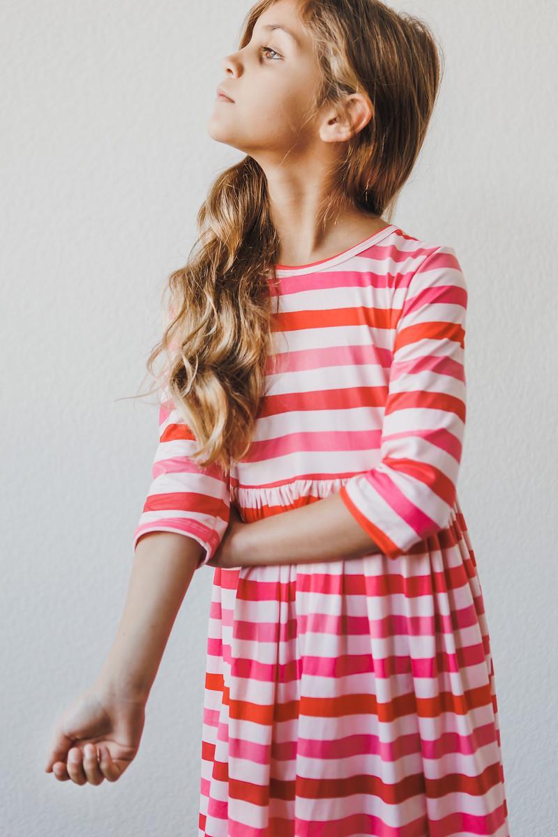 Girl stretching elegantly in the All You Need is Love 3/4 Sleeve Pocket Twirl Dress, emphasizing the fun and playful feel of this twirl dress for girls.