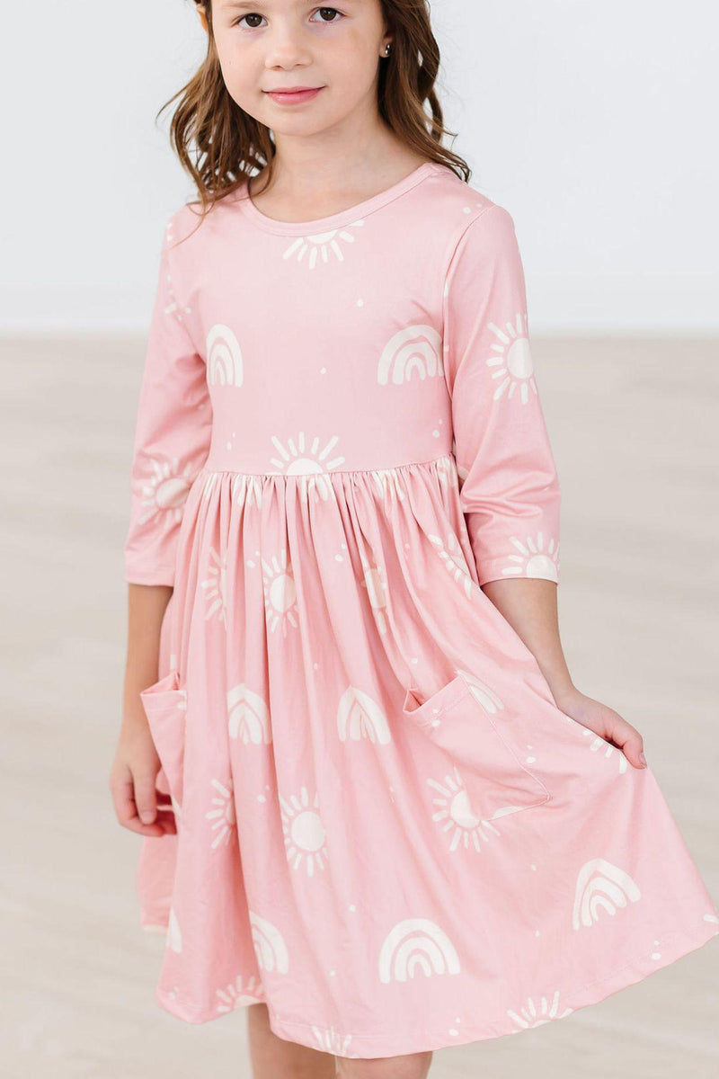 Soft Pink Suns 3/4 Sleeve Pocket Twirl Dress with a girl smiling, displaying the adorable design of sun motifs and pockets.