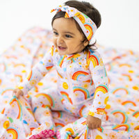 Baby wearing pink Here Comes the Sunshine SoftKnot Bow head-wrap with sun and rainbow print, CozyMa fabric.