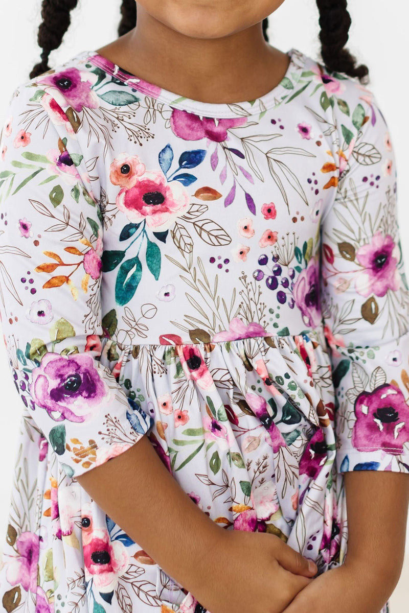 Close-up of a girl in the Midnight Rain 3/4 Sleeve Pocket Twirl Dress, highlighting the beautiful floral print and stylish scoop back design.