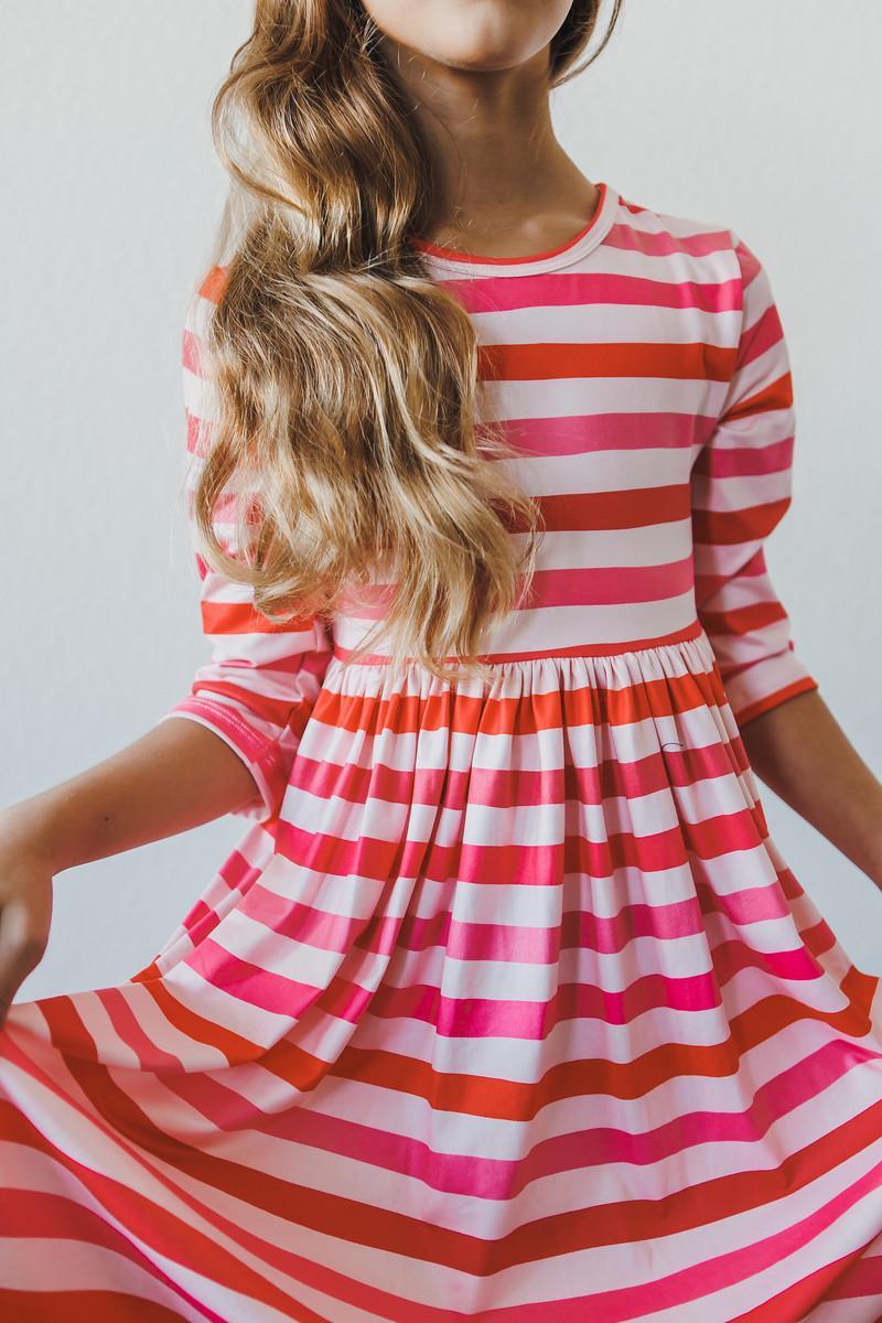 Girl wearing the All You Need is Love 3/4 Sleeve Pocket Twirl Dress, featuring vibrant pink and orange stripes, perfect as a twirl dress for girls.