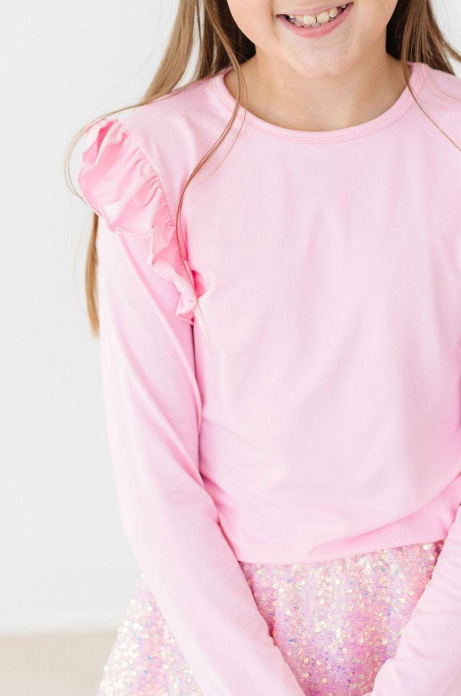 Bubblegum Pink L/S Ruffle Tee on a young girl, showcasing the stylish ruffle detail and vibrant pink color, perfect for playful outfits.