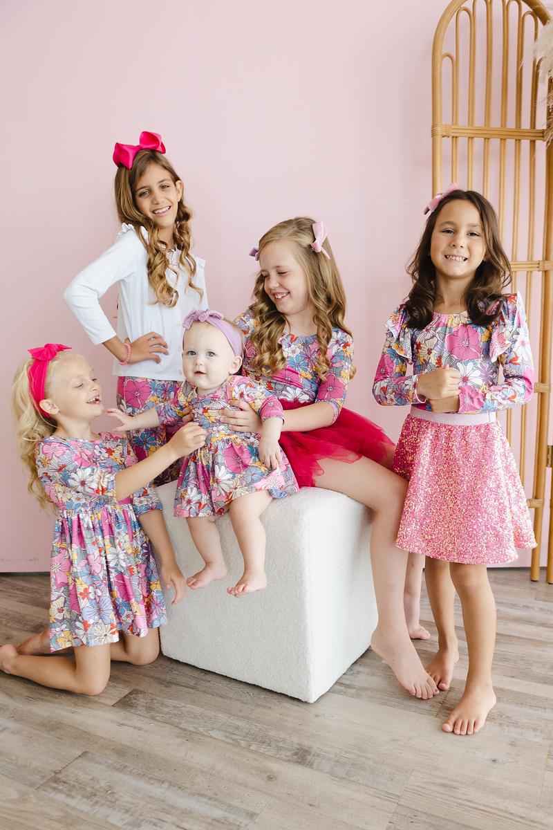 Group of girls in matching Mauve What's Up Buttercup 3/4 Tutu Leotards, enjoying a fun moment together, highlighting their colorful outfits and playful spirit.
