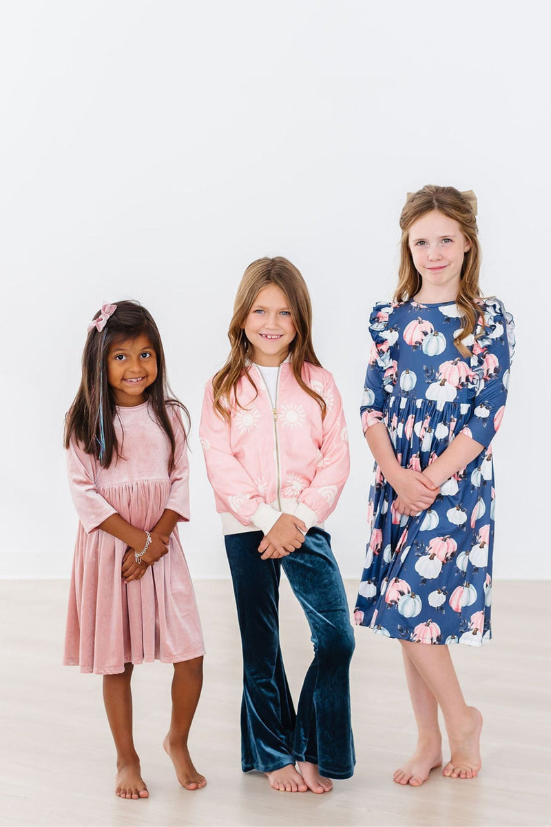 Three girls posing together, one in a Vintage Pink Velvet Twirl Dress, highlighting its stylish appeal among playful outfits.
