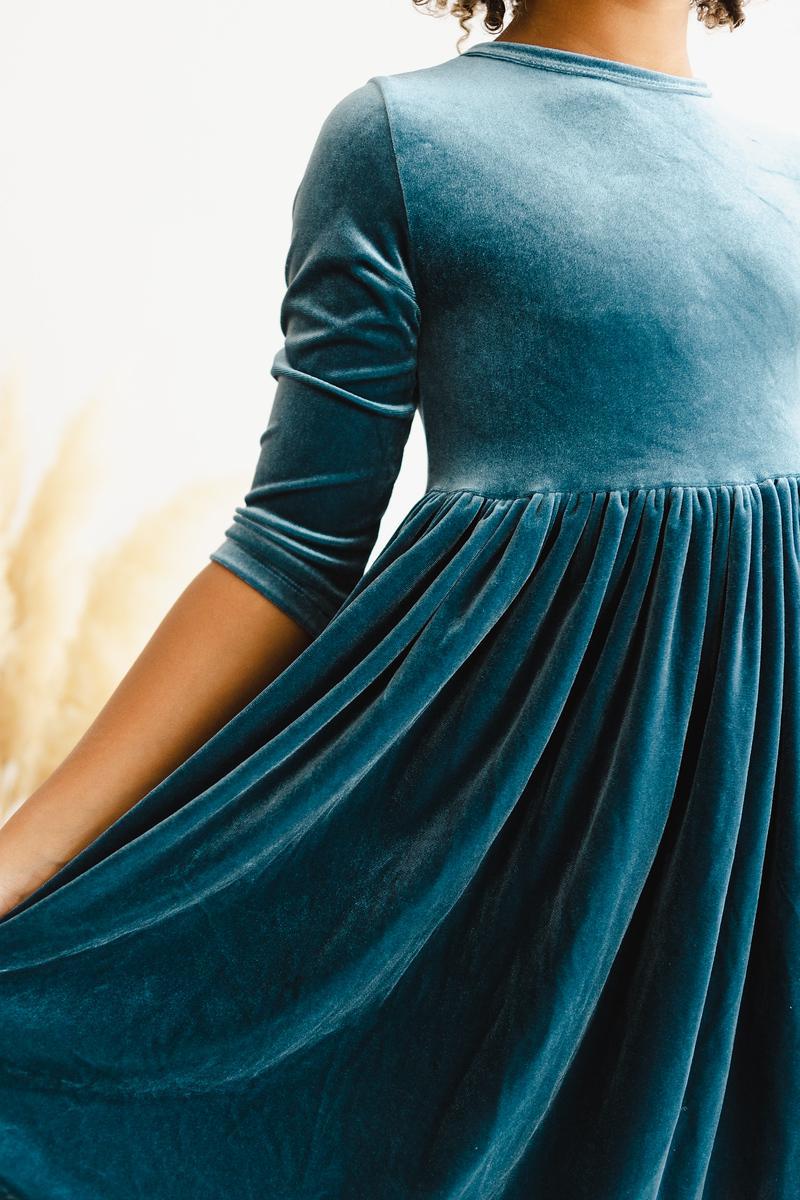 Close-up of the Denim Blue Velvet Twirl Dress for Girls, showcasing the luxurious fabric and subtle pleats for a twirling effect.