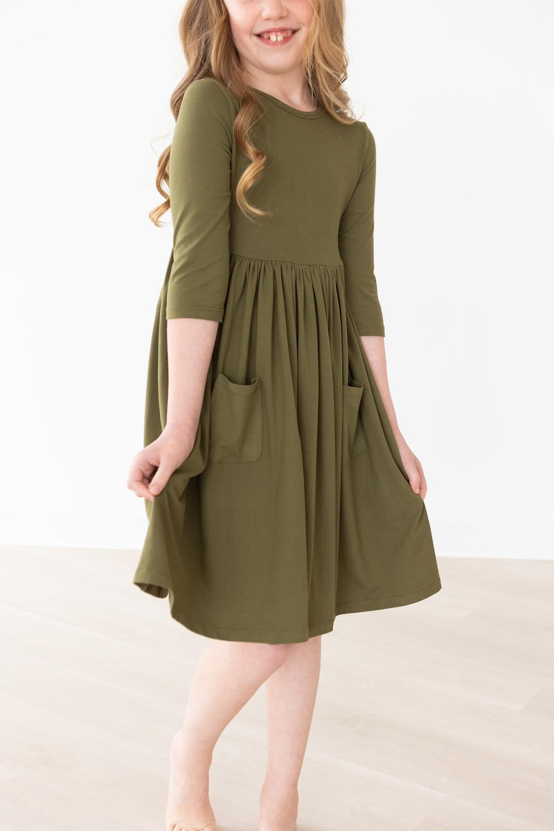 Young girl smiling while wearing the Olive 3/4 Sleeve Pocket Twirl Dress by Mila & Rose, showcasing the elegant design and full skirt perfect for twirling.