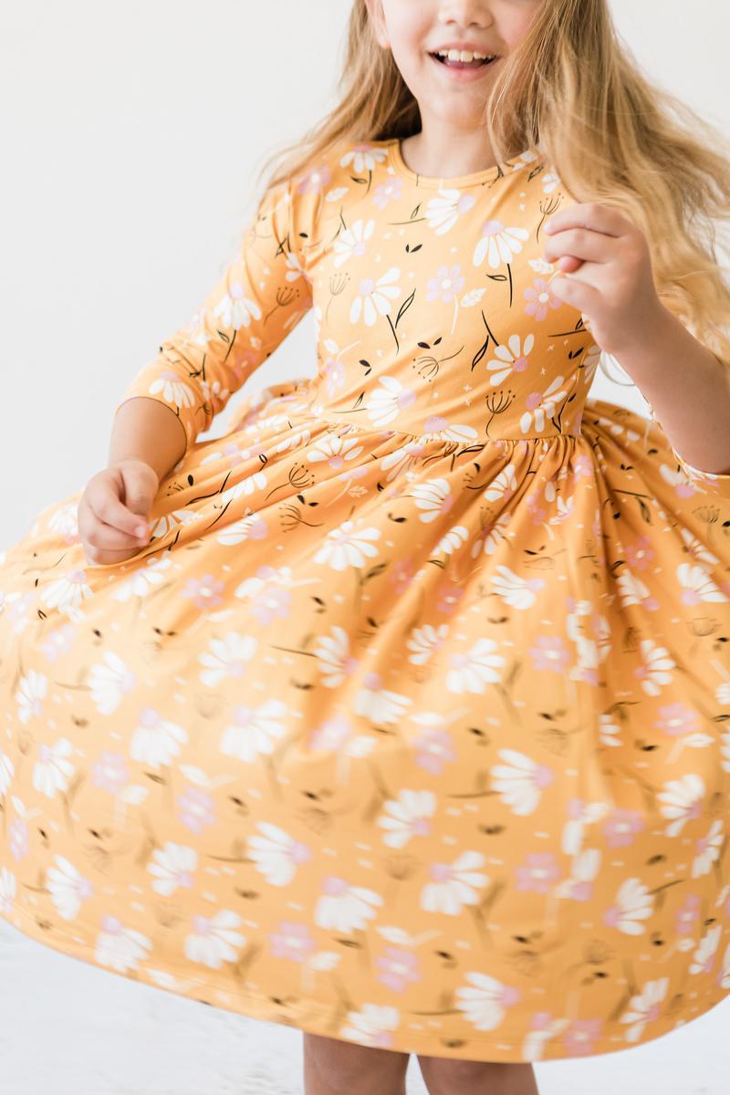 A joyful little girl wearing the Dandelions in Fall 3/4 Sleeve Pocket Twirl Dress for Girls, twirling with delight during playtime.