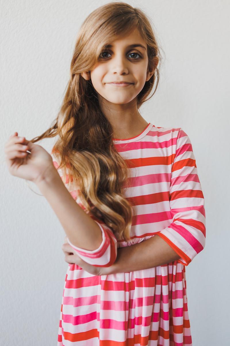 Girl confidently posing in the All You Need is Love 3/4 Sleeve Pocket Twirl Dress, highlighting the playful striped design, a must-have twirl dress for girls.