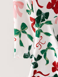 White dress fabric featuring festive red, green, and pink bow prints for girls' Christmas holiday wear.