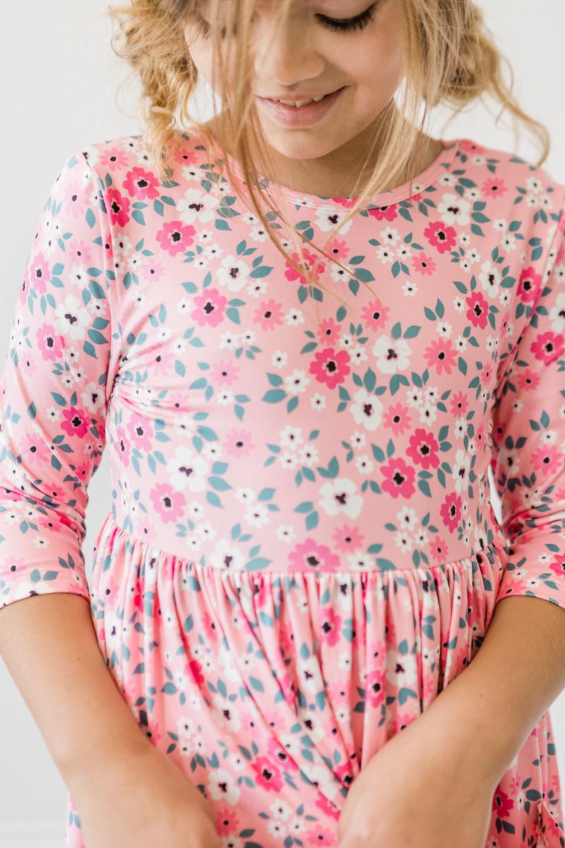 Smiling girl wearing the Azalea 3/4 Sleeve Pocket Twirl Dress, featuring a pretty floral pattern and a comfortable fit.