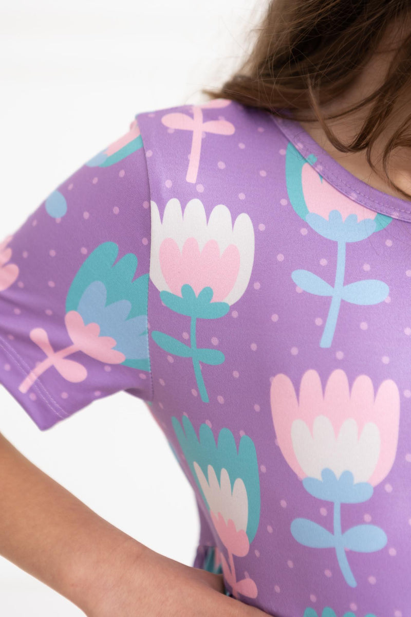 Close-up of the fabric pattern on the Too Cool Tulips S/S Pocket Twirl Dress by Mila & Rose, featuring colorful tulips on a purple background, ideal for little fashionistas.