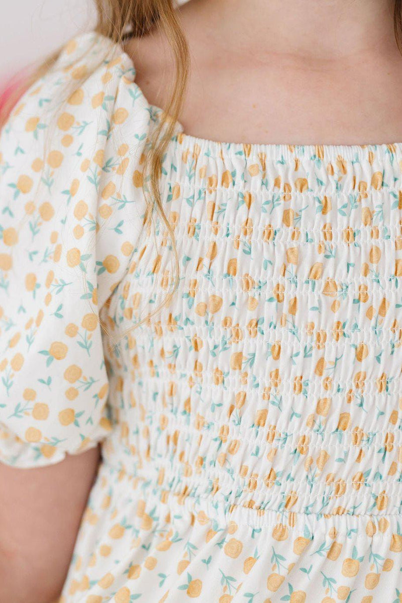Close-up of the smocked bodice of the Marvelous Marigolds Smocked Ruffle Dress, highlighting the comfortable, stretchy design and floral pattern.
