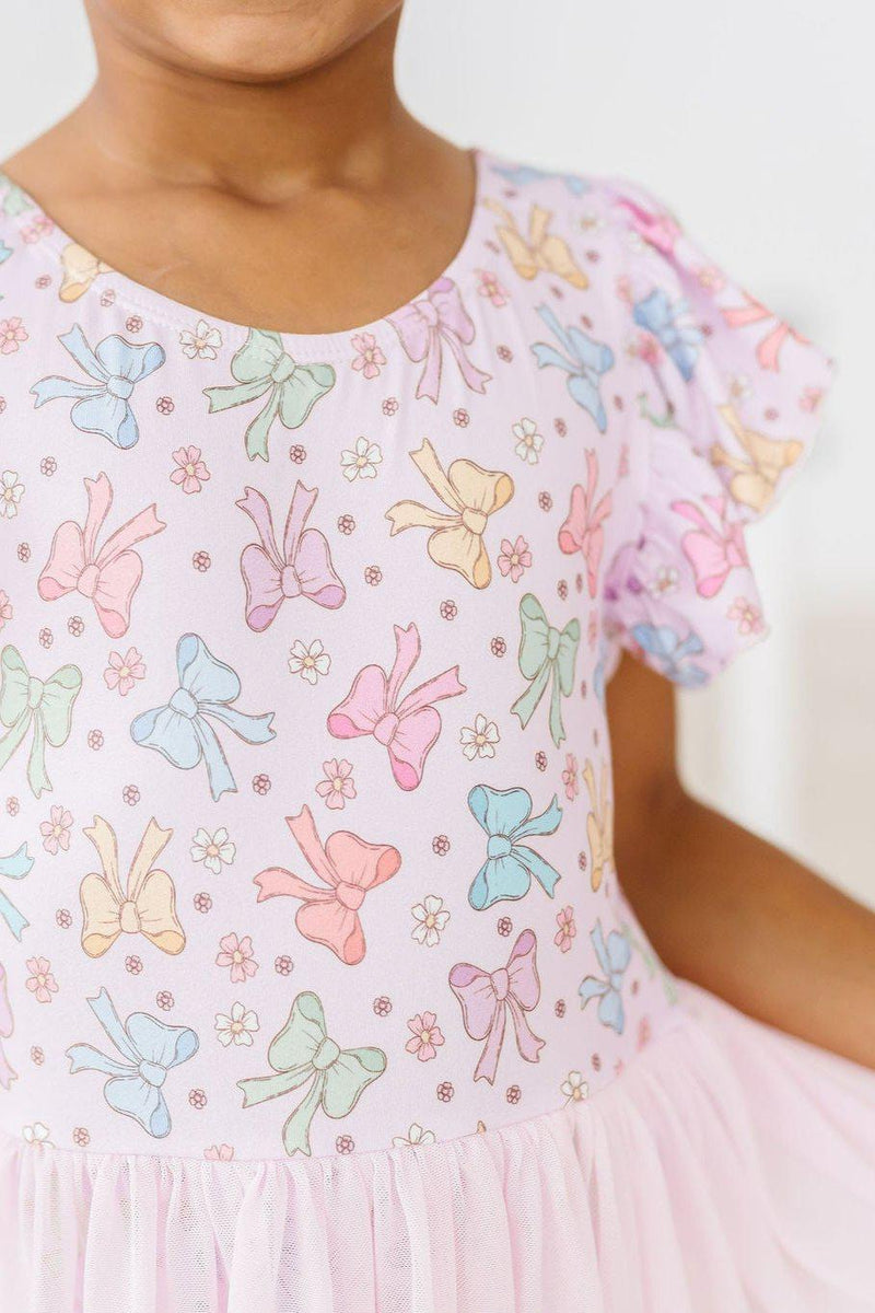 Detailed view of the bow print on the Springtime Bows Short Sleeve Twirl Leotard by Mila & Rose, highlighting the pastel colors and floral accents.