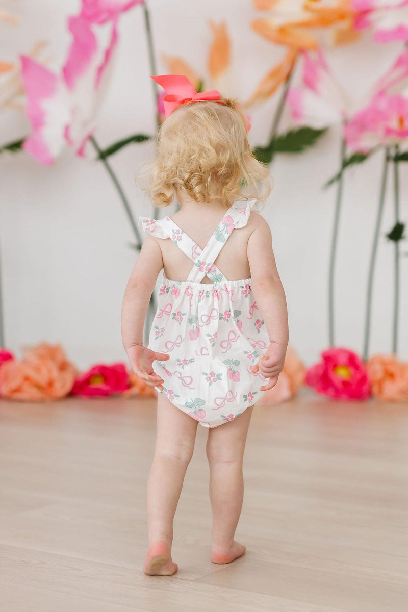 Close-up of the Berries & Bows Ruffle Cross Back Romper, featuring the soft polyester and spandex blend for comfort during play.