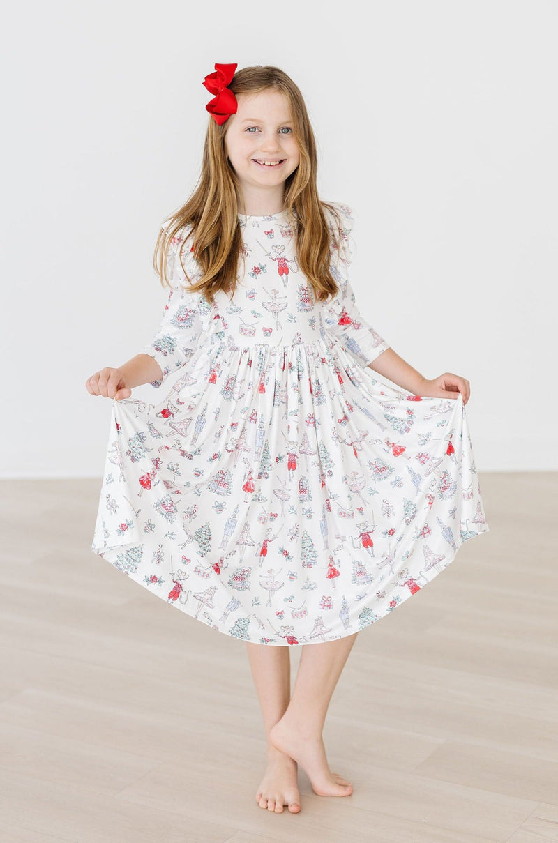 A joyful girl model in Clara's Christmas 3/4 Sleeve Ruffle Twirl Dress, twirling to show off the festive print and ruffle details, ideal for festive occasions.