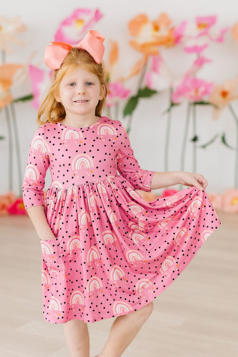 Child happily twirling in the Rainbow Wishes 3/4 Sleeve Pocket Twirl Dress by Mila & Rose®, highlighting the cute pocket design and colorful rainbows.