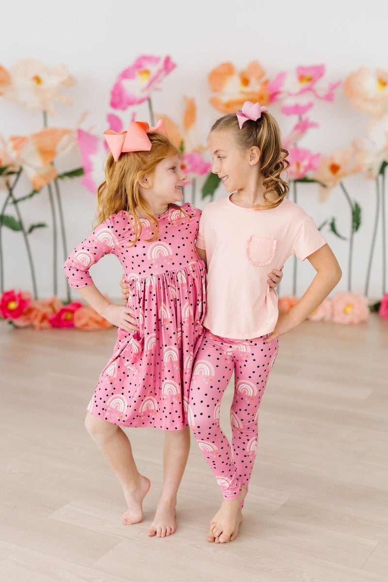 Two cute girls having fun while dressed in the Peach Ruffle Pocket Tee, highlighting playful style and friendship.