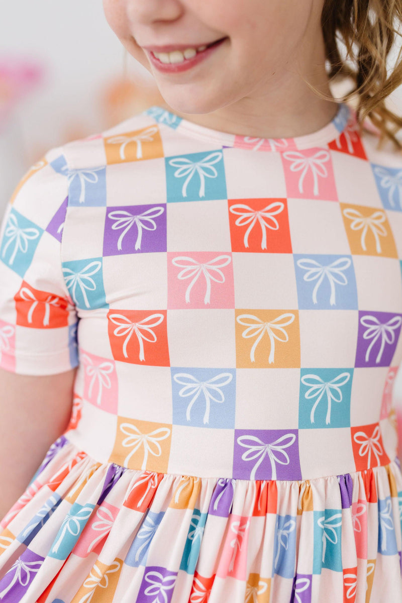 Colorful close-up of the Rainbow Ribbons S/S Pocket Twirl Dress fabric, emphasizing its soft texture and flexibility for active kids.