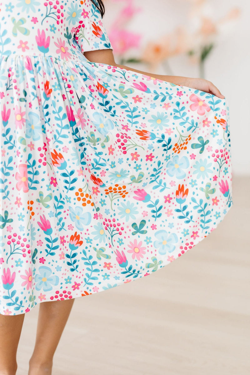 Close-up of the twirly skirt of the Sunlit Garden S/S Pocket Twirl Dress, featuring a cheerful floral pattern and playful movement.