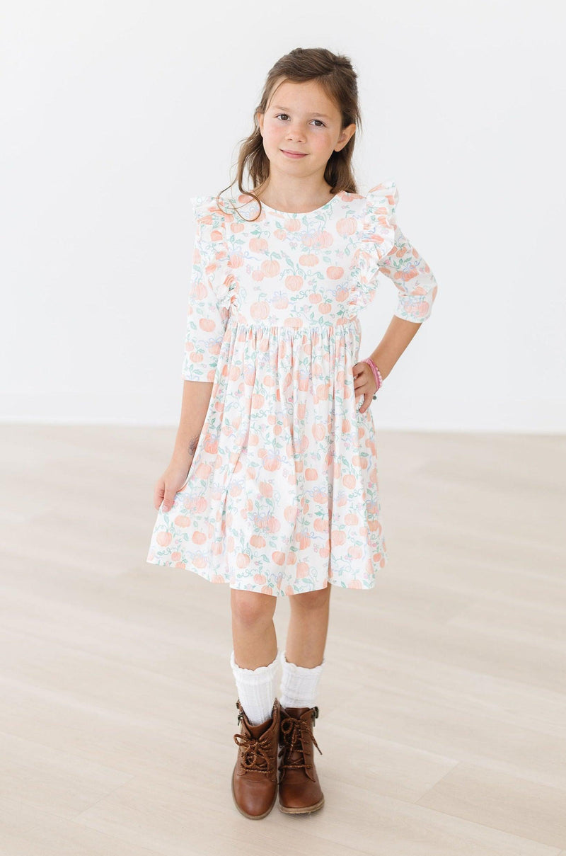 Close-up of the delightful ruffle detail of the Pretty Pumpkins Ruffle Twirl Dress, capturing the fun and flair perfect for playground spins.