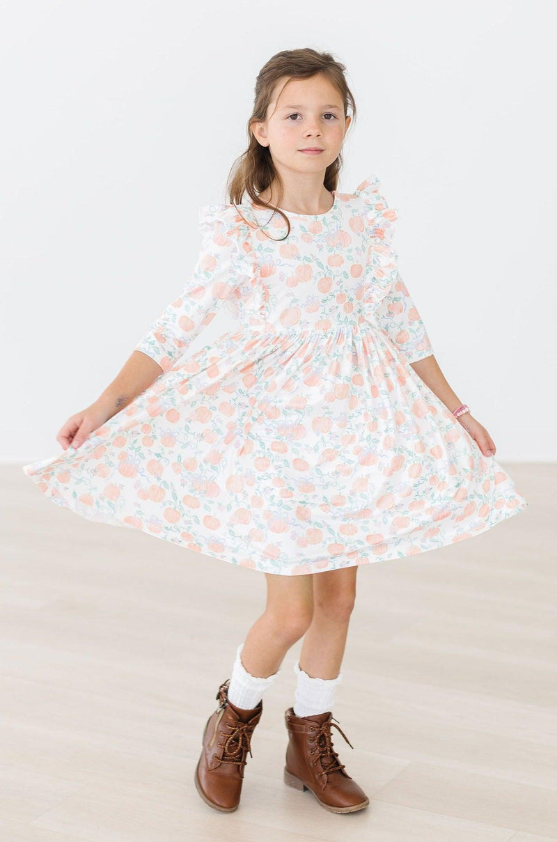 A complete outfit featuring the Pretty Pumpkins Ruffle Twirl Dress paired with twirl shorts, creating a stylish look for any pumpkin patch outing.