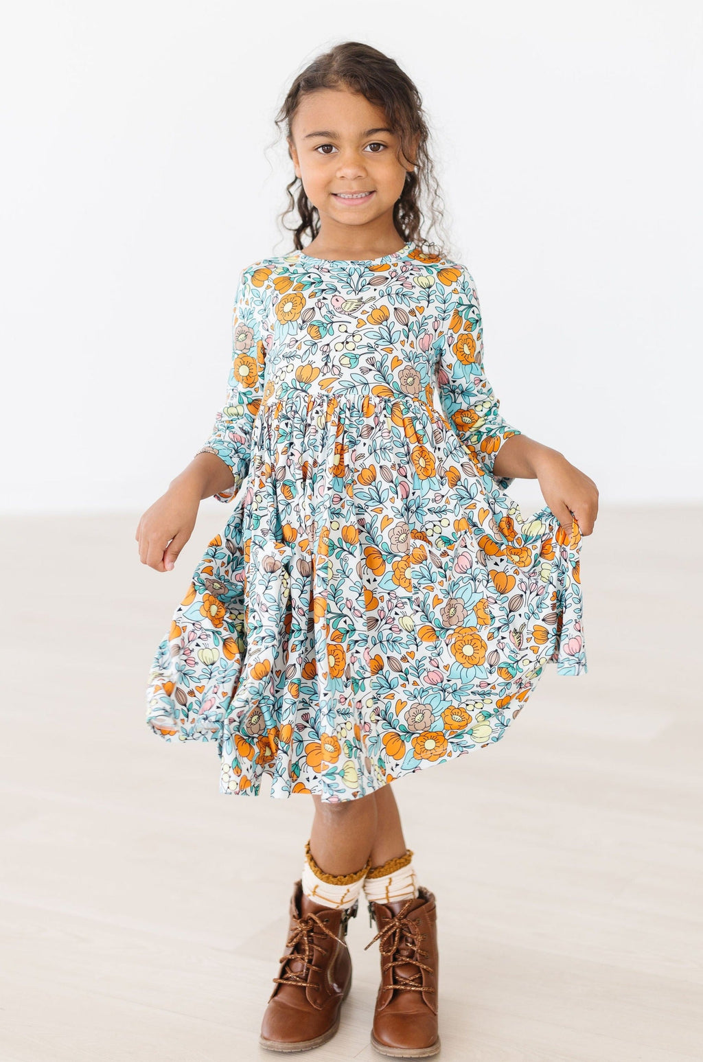 Girl smiling in a Vintage Vibes 3/4 Sleeve Twirl Dress for Girls featuring a colorful floral pattern, perfect for twirling and dancing.