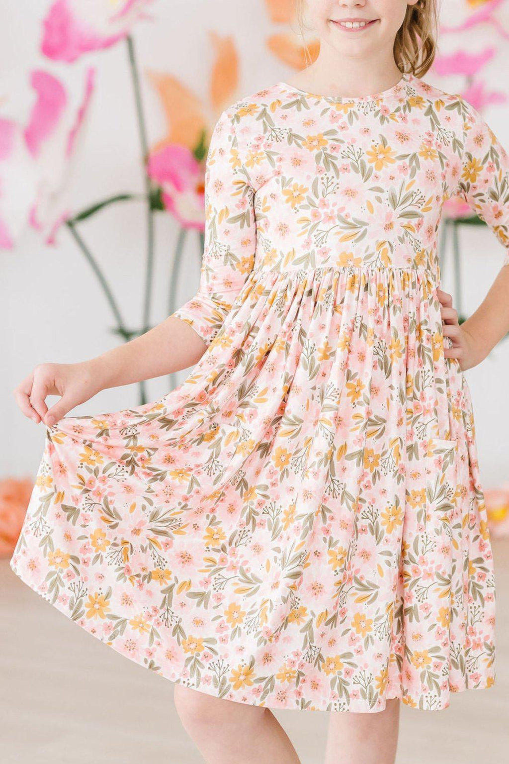 Pretty Peachy 3/4 Sleeve Pocket Twirl Dress worn by a smiling girl, showcasing its floral design and twirl-friendly skirt.