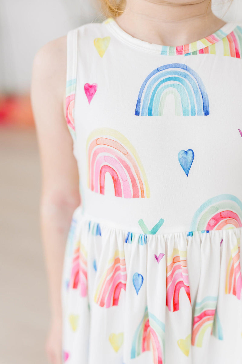 Close-up of a young girl's upper body in the Radiant Rainbows Tank Twirl Dress, highlighting the vibrant rainbow designs and soft fabric.