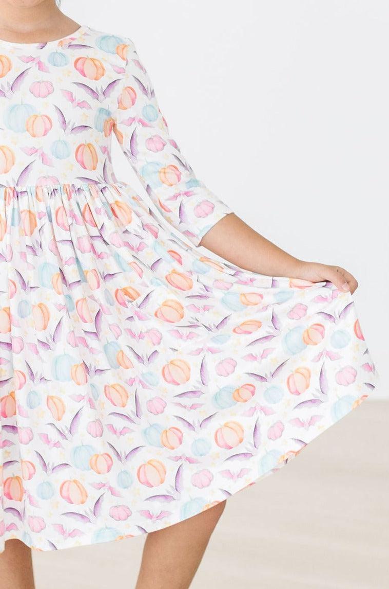 Close-up of the twirl design of the Spooky Sweetheart 3/4 Sleeve Pocket Twirl Dress, highlighting the vibrant pumpkin and bat pattern ideal for festive occasions.