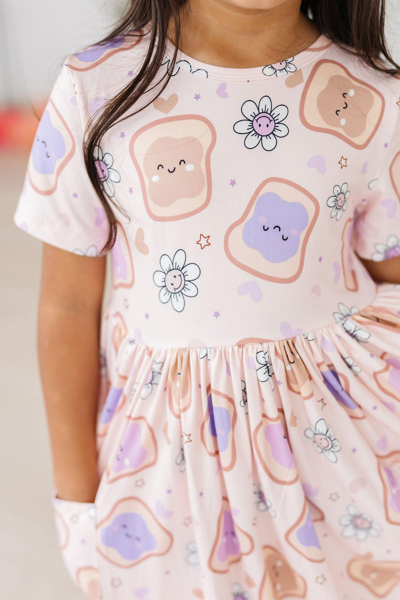 Close-up of the Peanut Butter Jelly Time S/S Pocket Twirl Dress by Mila & Rose, showcasing a fun design with cute sandwich graphics and flower patterns.