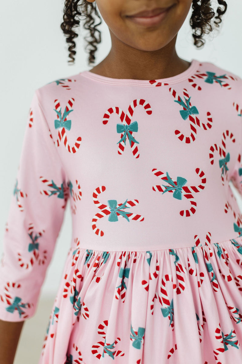 Close-up of the Candy Cane Cutie 3/4 Sleeve Pocket Twirl Dress by Mila & Rose, highlighting the playful candy cane and bow print design, perfect for Christmas.