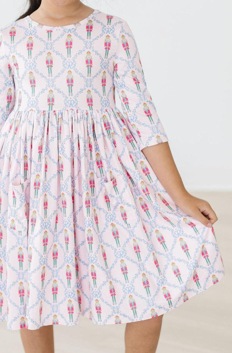 Close-up of a child modeling the Pink Nutcracker 3/4 Sleeve Pocket Twirl Dress, showcasing its twirl-friendly design and charming nutcracker pattern.